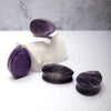 Purple Amethyst Tear drop Plugs - Amethyst plugs in the shape of a teardrop! Unique in shape, smooth edging and vibrant colour. A group of tear drop plugs arranged on a white background.